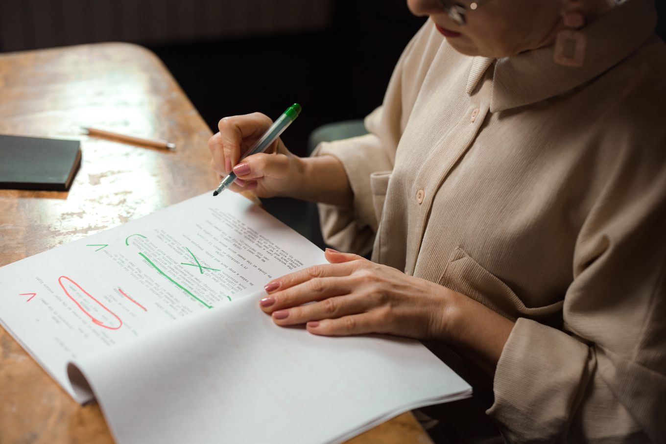Person marking corrections in green and red pen on a printed page