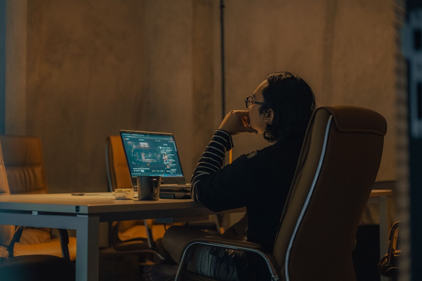 Freelancer working on a laptop at a desk in the evening with a cup of coffee