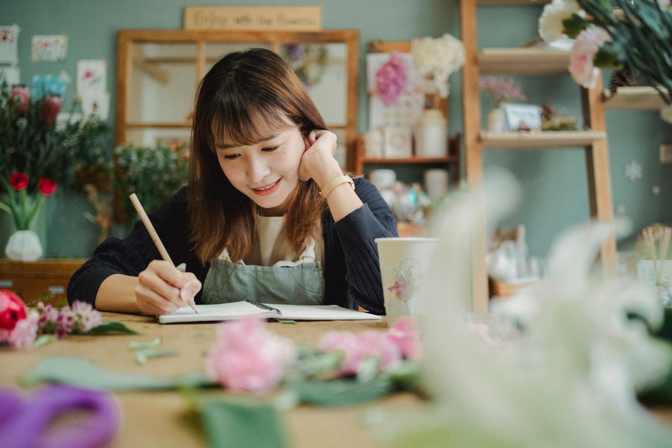 Small flower shop owner writing notes at her counter