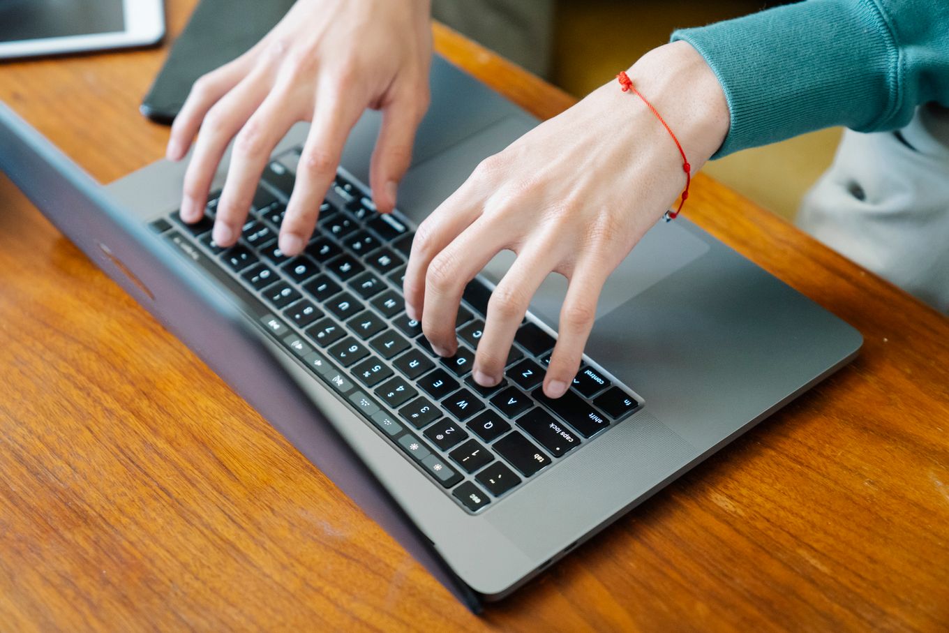 Freelancer typing on a laptop at a wooden desk