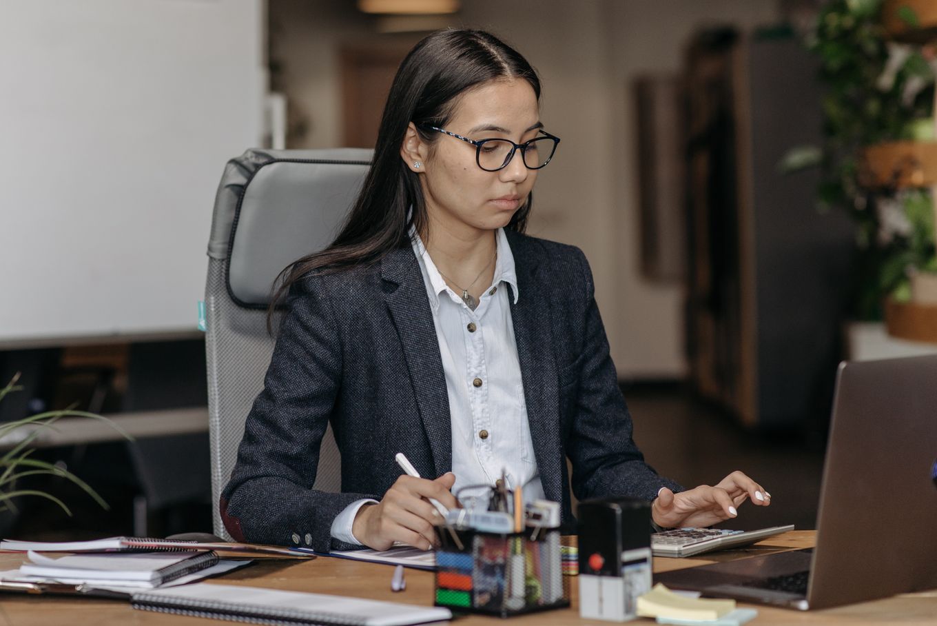 Office employee working with a calculator and laptop at her desk