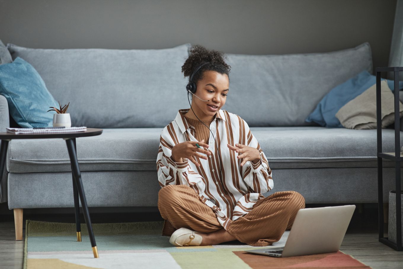 Freelancer wearing a headset talking to a client on a laptop video call at home