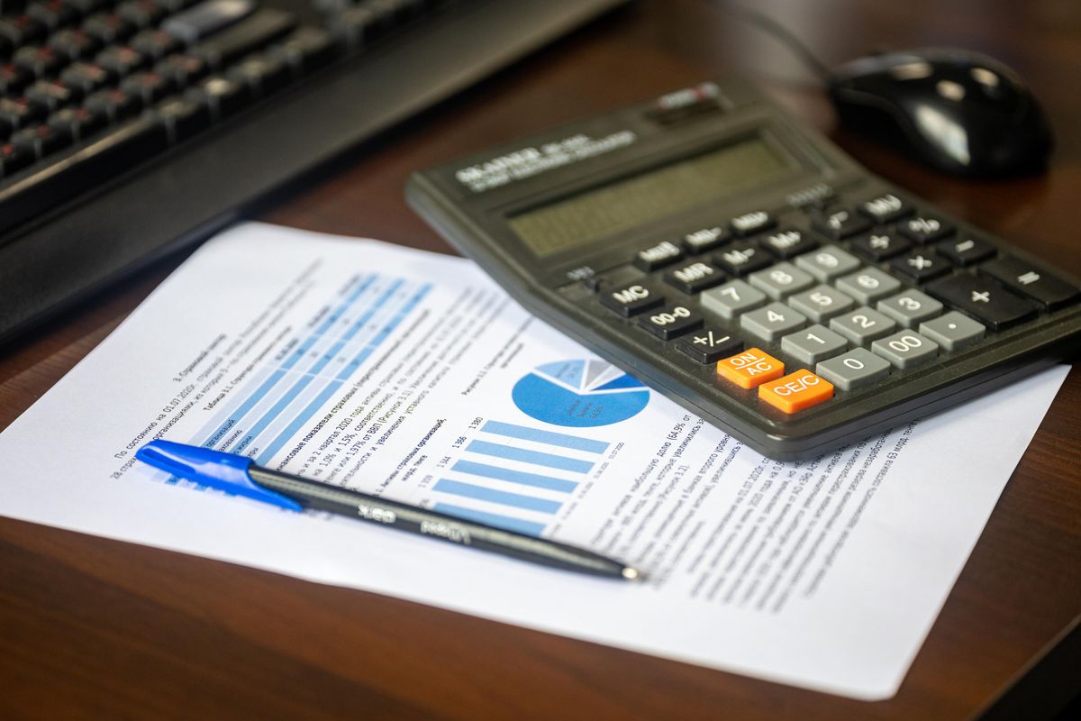 Calculator resting on a printed financial report with charts