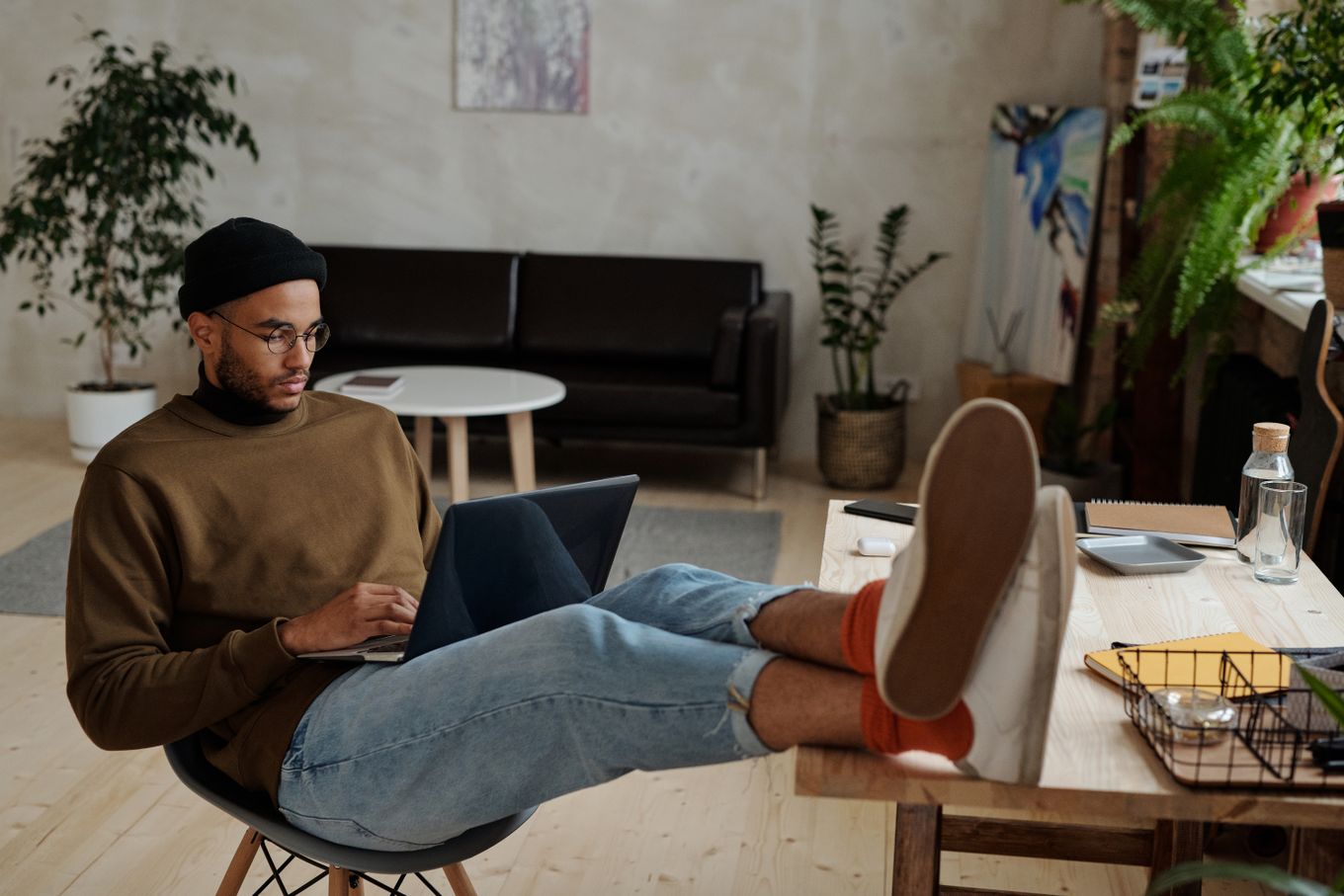 Freelancer working on a laptop in a plant-filled home office
