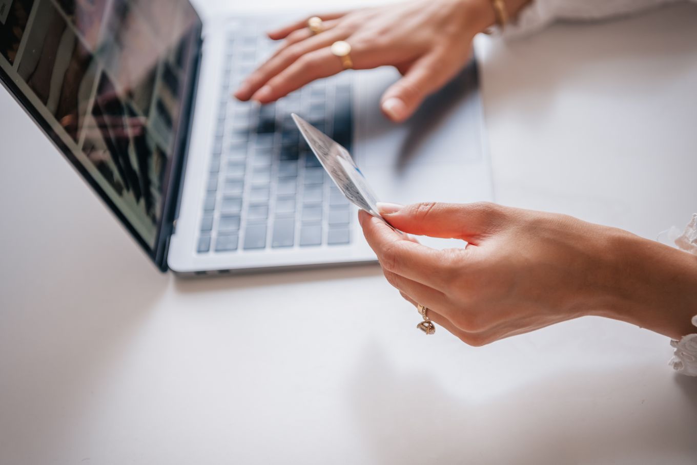 Hands holding a bank card while typing on a laptop to pay online