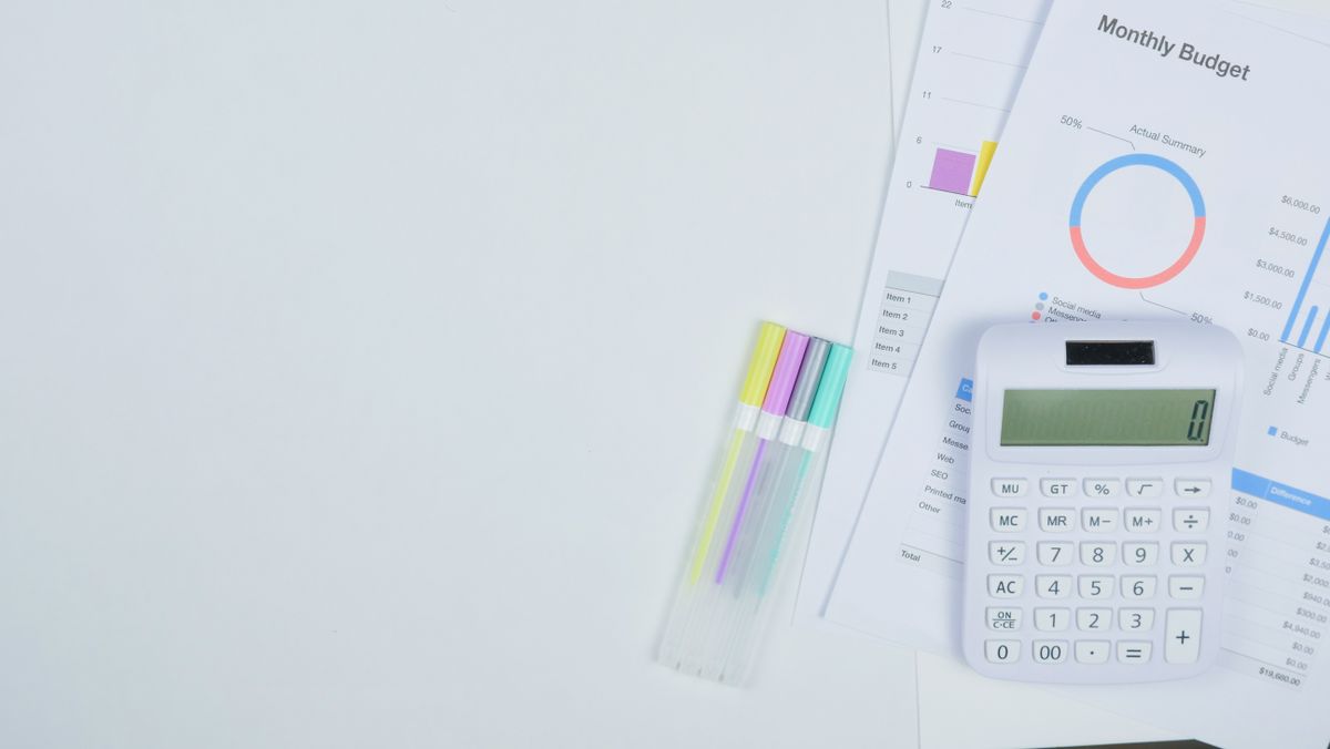Monthly budget planning sheet with charts and a calculator on a desk