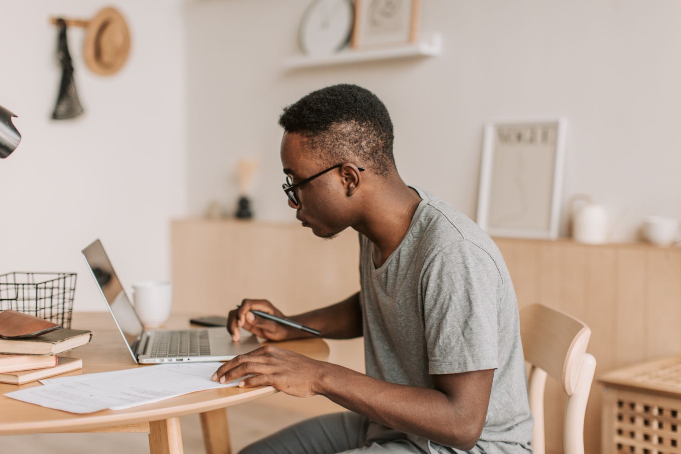 Freelancer taking notes while working on a laptop at a home desk