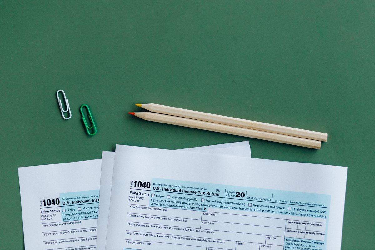 U.S. 1040 tax forms laid out on a desk with pencils and paperclips