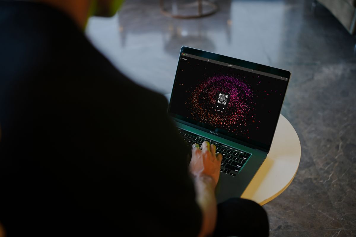 Person interacting with a QR code displayed on a laptop screen
