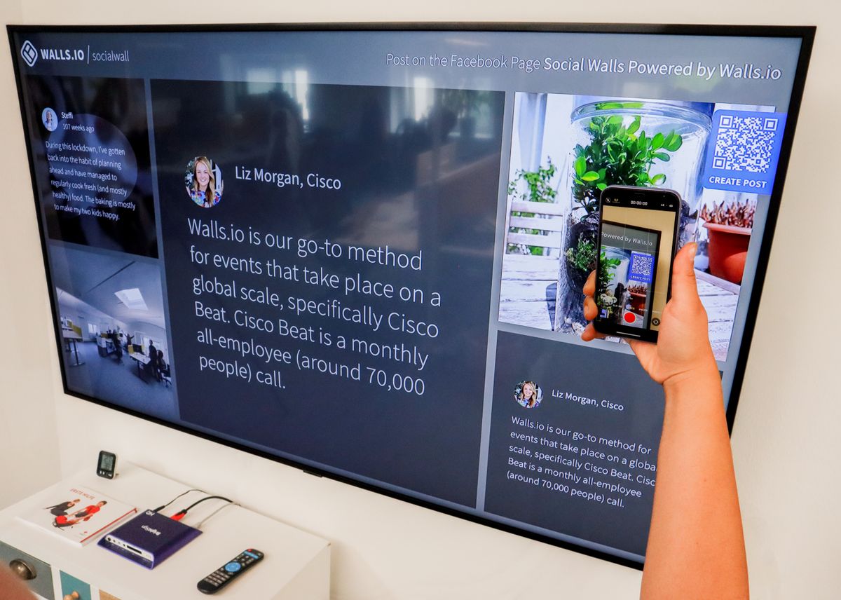 Person using a smartphone to scan a QR code displayed on a large screen