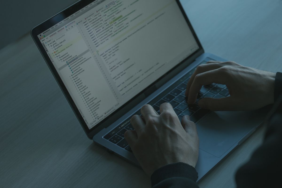 Close-up of hands on a laptop keyboard in a dark, focused workspace