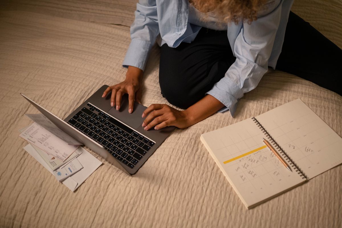 Freelancer working on a laptop with invoices and a notebook spread out beside it