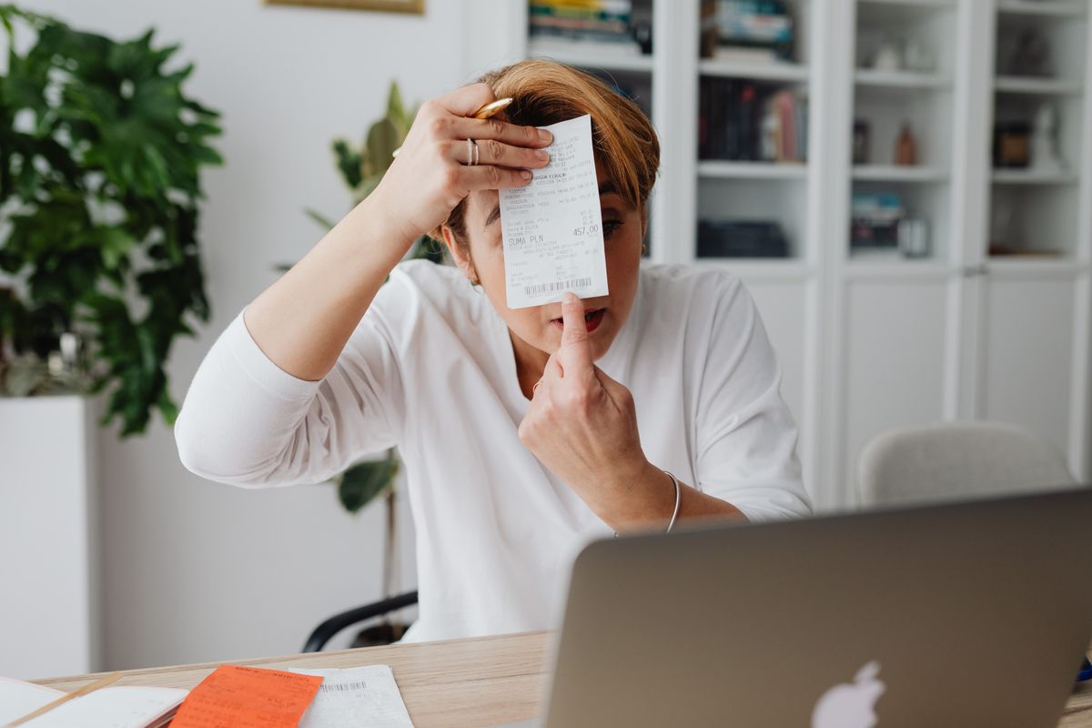 Person holding up a receipt and examining the charges on it closely