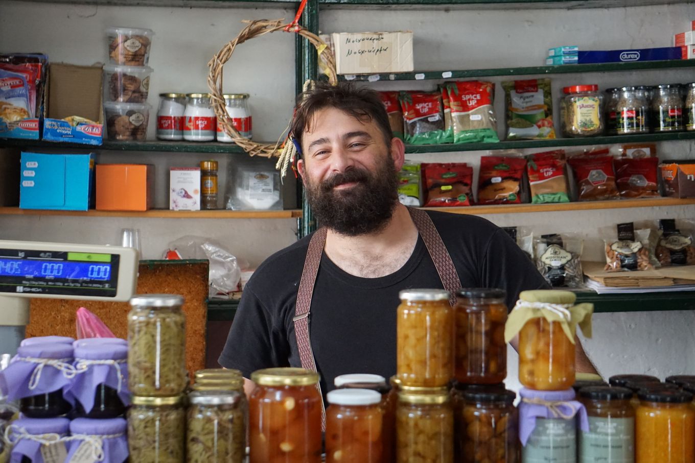 Shopkeeper standing behind shelves of priced homemade preserves