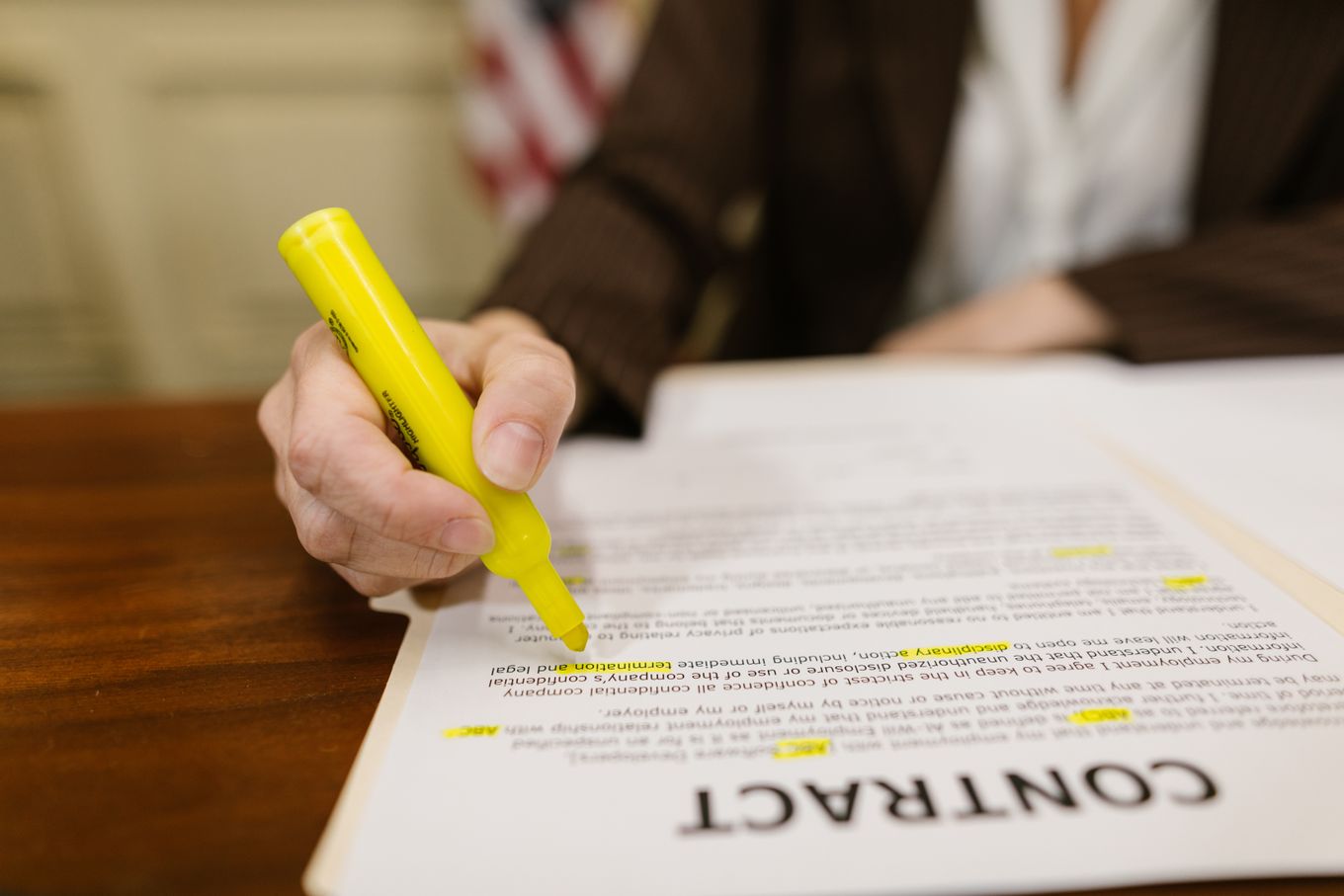 Hand highlighting terms in a printed contract