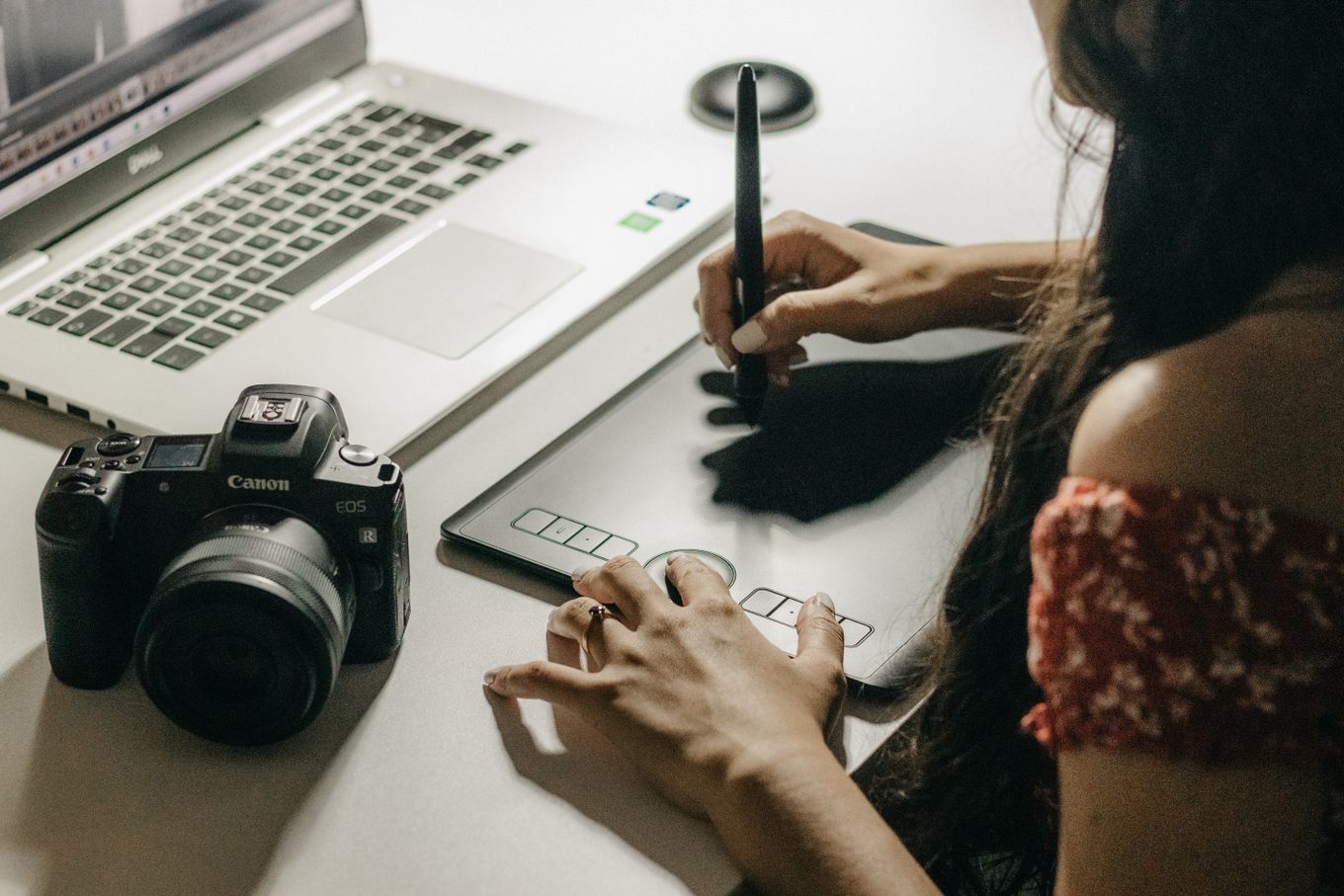 Freelance designer drawing on a graphics tablet next to a laptop and a camera